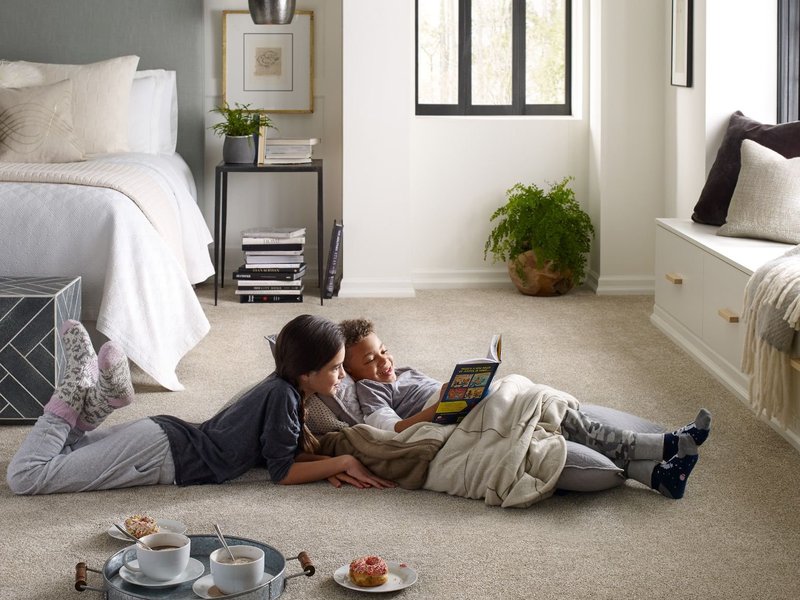 Family of two sitting on a Carpet installed by the experts at Verona Carpet Shop in Verona, New Jersey