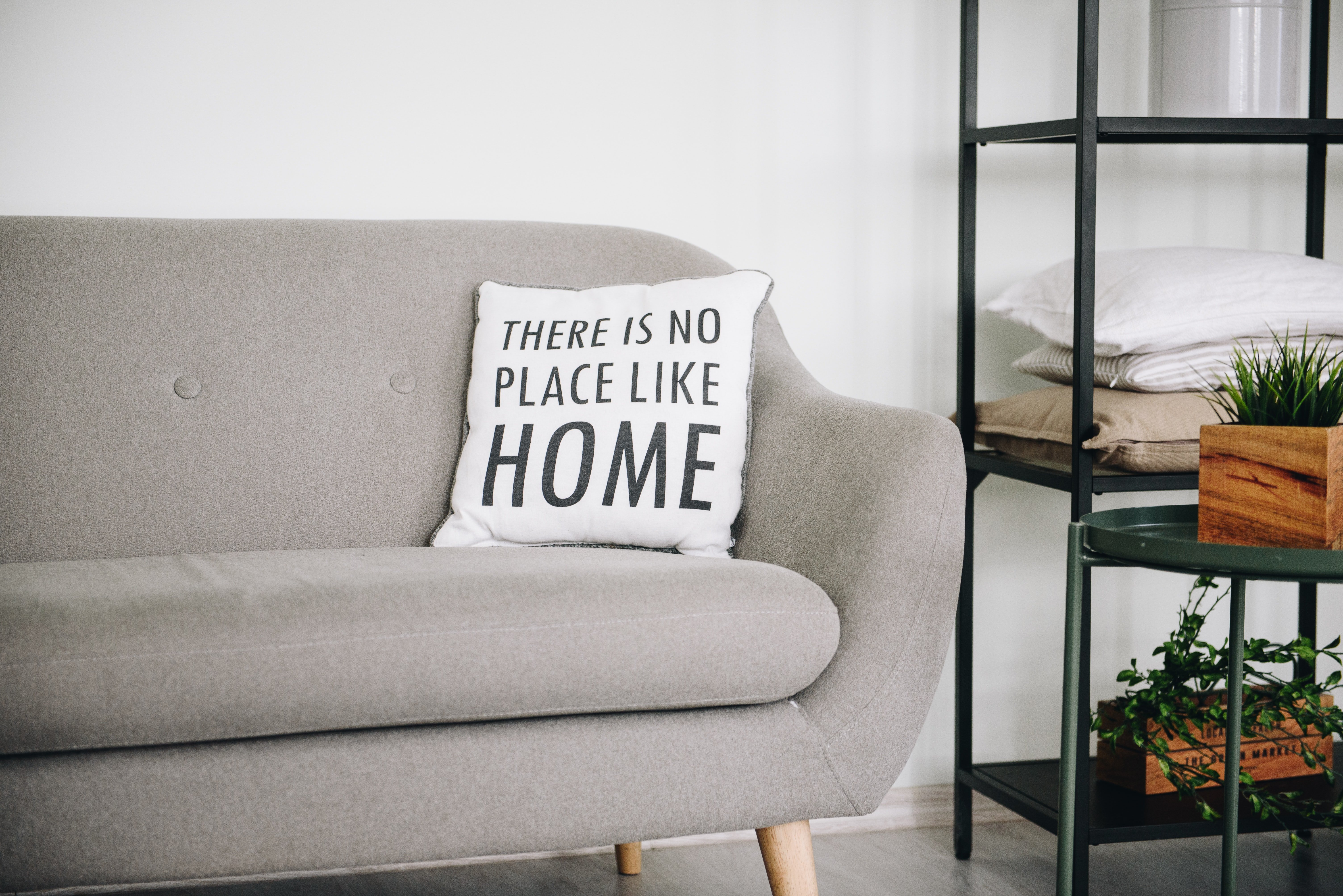 grey sofa with white pillow and black shelf